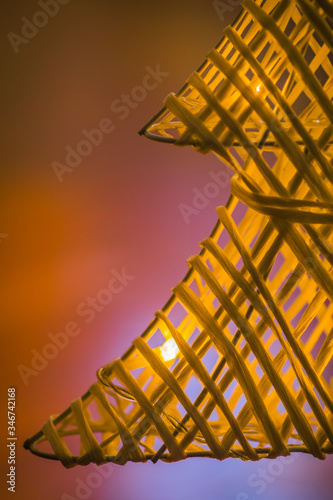 Detail of small woven christmas tree from strands or straws with warm white led lights on it. Artificial christmas tree in white color standing on the floor photo