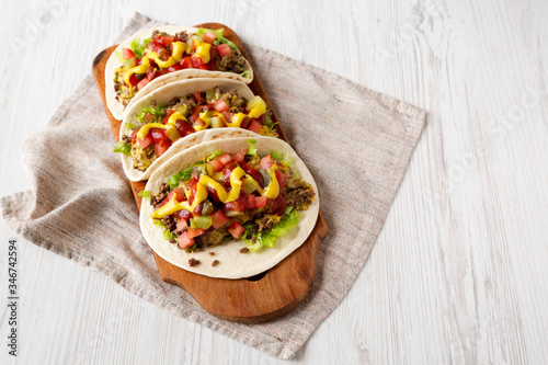 Homemade Cheeseburger Tacos on a rustic wooden board on a white wooden background, low angle view. Copy space.