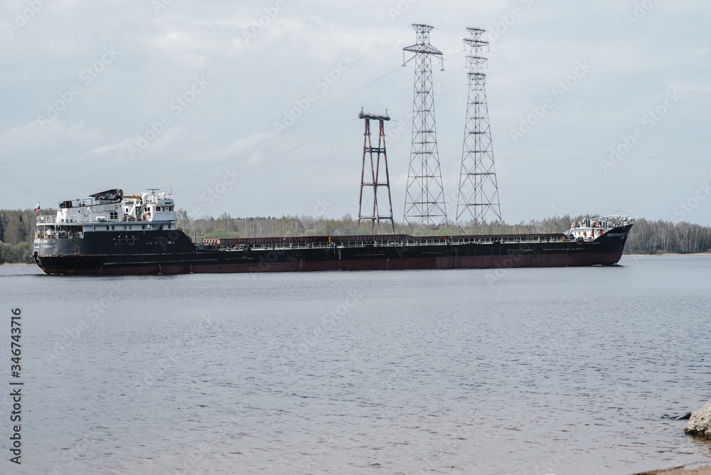 .a large empty barge floats on the river. side view
