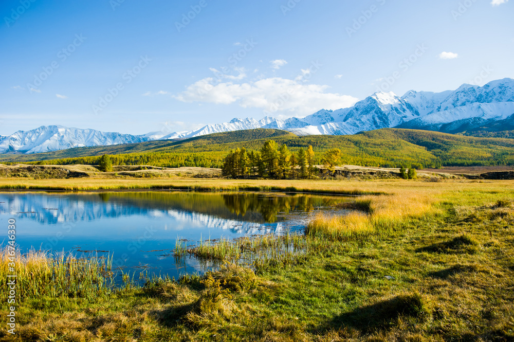 lake and mountains, Altai, autumn day. Reflections in the lake, yellow withered grass.