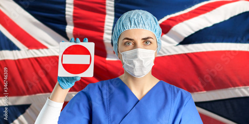 health, medicine and pandemic concept - young female doctor or nurse wearing face protective mask for protection from virus disease and hat showing stop sign over flag of united kingdom on background