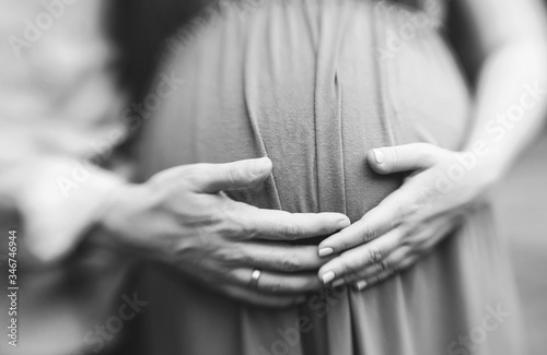 male and female hands on belly of pregnant woman