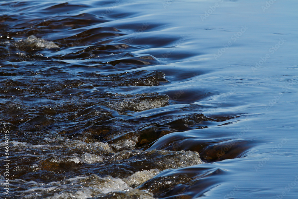 Fototapeta premium A line of rocks in hard flowing stream in Finnish rapids