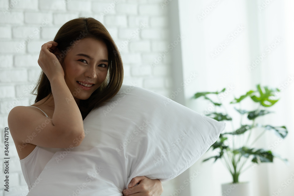 Asian woman cheerful and healthy and wearing white pajamas wake up on bed in bedroom in the morning.at home in holiday. Asian woman cheerful and healthy and wearing white pajamas wake up on bed in bedroom in the morning.at home in holiday.