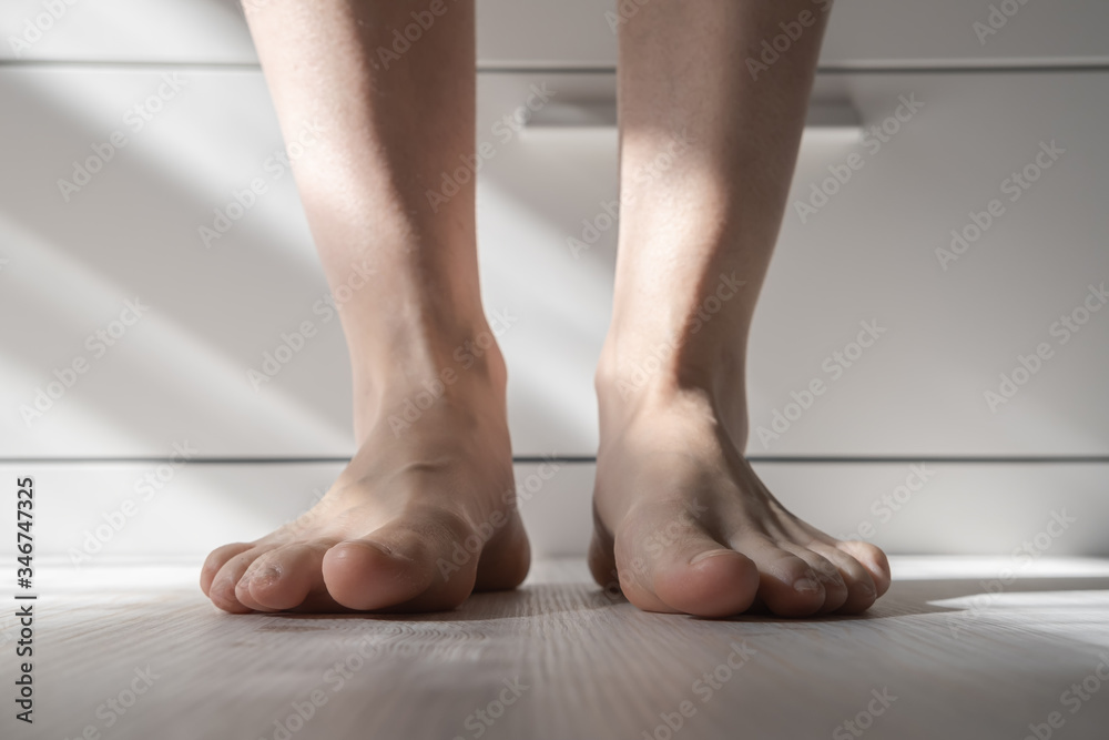 Bare feet in the sunlight, on a blurred background of a white couch. Bottom view. Bare feet in the sunlight, on a blurred background of a white couch. Bottom view.