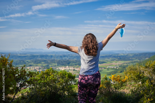 girl on her back with a mask in her hand, in a rural landscape