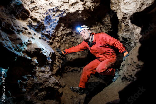 Photography Man walking and exploring dark cave with light headlamp underground