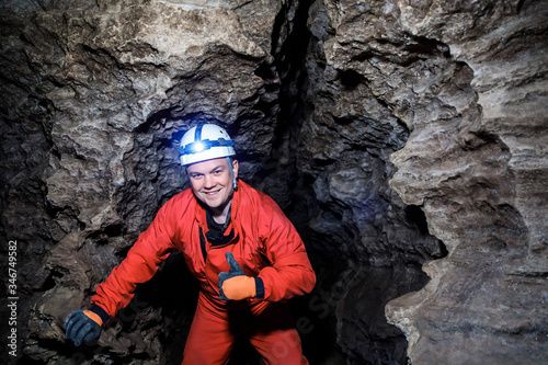 Schilderij op canvas Man walking and exploring dark cave with light headlamp underground