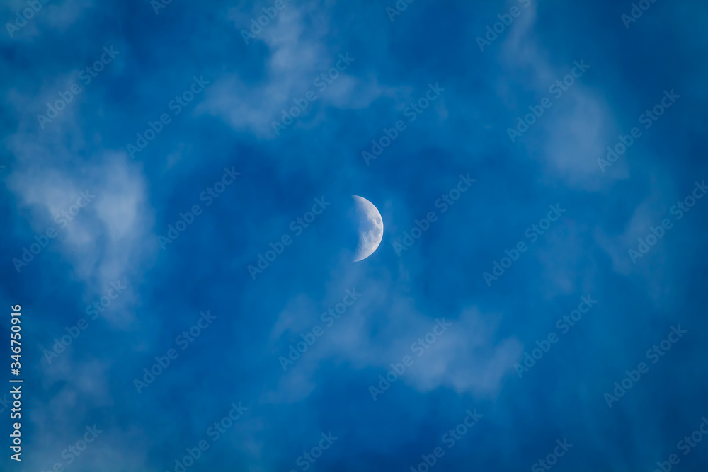 half moon in overcast blue sky with fume clouds half moon in overcast blue sky with fume clouds