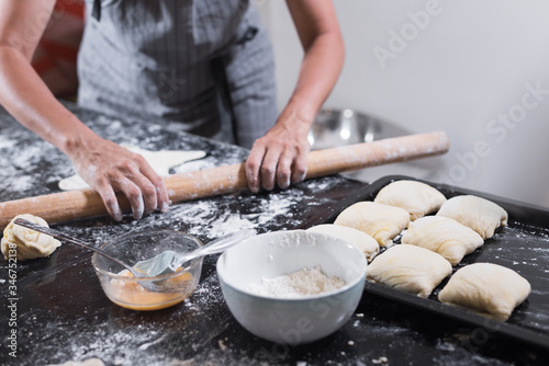 Young woman rolling dough with long pin for samsa cooking at home.