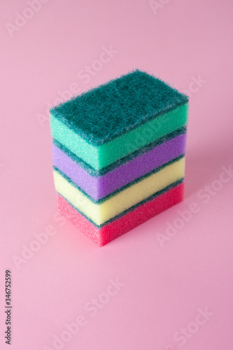 Kitchen cleaning sponge on pink background. Stack of multi-colored sponges.