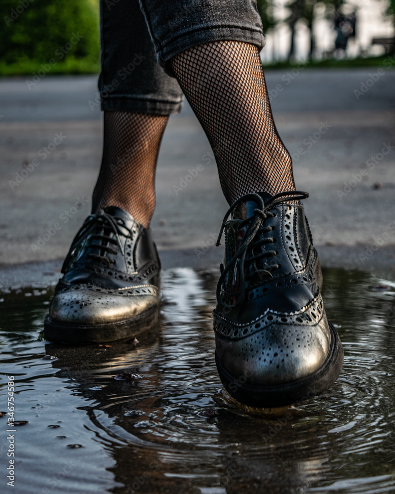 Black silver woman brogue shoes stepping in the rain puddle