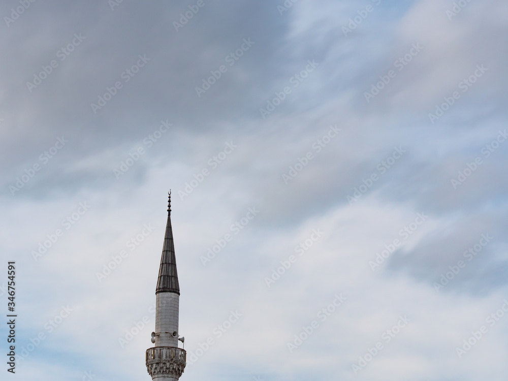 Minaret of a Muslim mosque on the background of the cloudy sky.