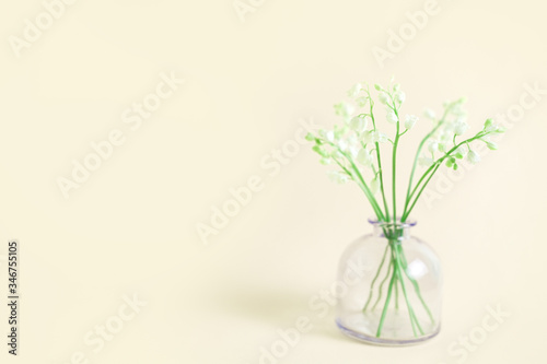 Fototapeta Naklejka Na Ścianę i Meble -  Greeting card with white lily of the valley on beige background for celebration Mothers Day, wedding, March 8. Nature concept. Home garden in vase. Summer green floral design. Selective focus.