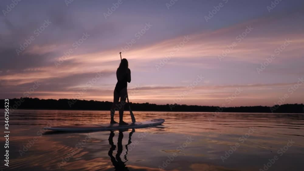 Girl taking a break from paddling SUP to enjoy beautiful sunset Girl taking a break from paddling SUP to enjoy beautiful sunset