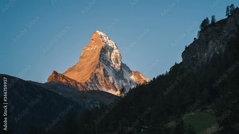 Time lapse of early morning golden sunlight slowly covering the Matterhorn mountain peak in the alps of Switzerland at sunrise