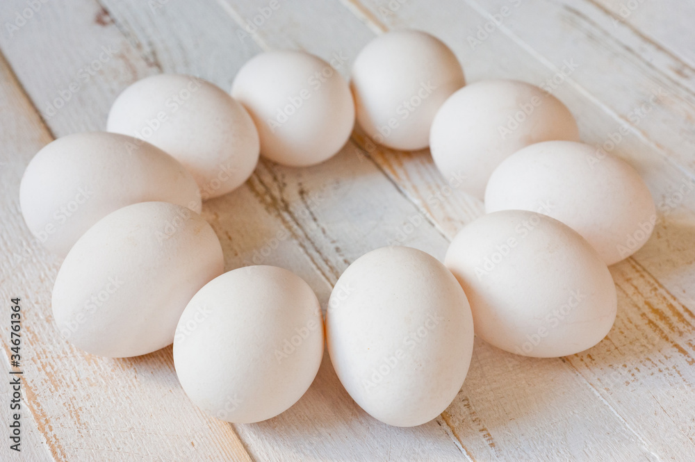 White chicken eggs lying on a white painted wooden surface. Background for livestock products. White chicken eggs lying on a white painted wooden surface. Background for livestock products.