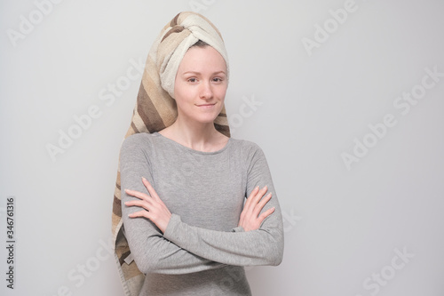 Young girl with a towel on her head. Happy and smiling woman on a grey background.