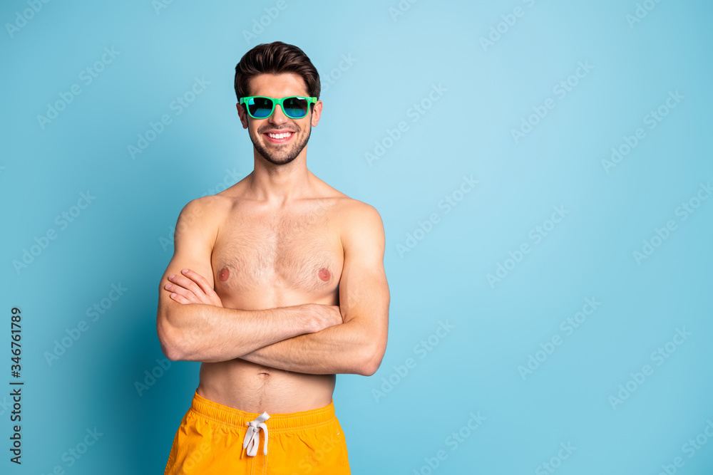 Photo of cheerful positive toothy beaming man standing with arms crossed near empty space isolated pastel blue color background