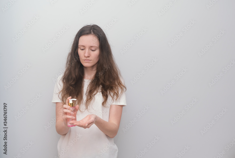 Young girl holding hand antiseptic, disinfectant on a grey background. Young girl holding hand antiseptic, disinfectant on a grey background.