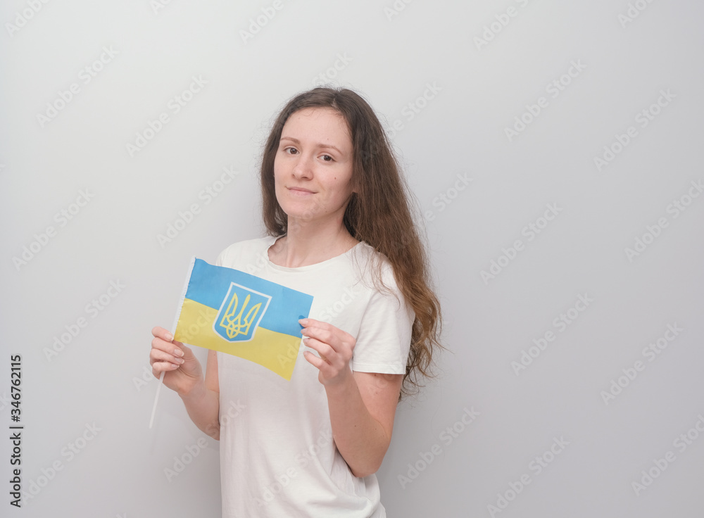 Happy girl holding Ukrainian flag on the grey background. Happy girl holding Ukrainian flag on the grey background.
