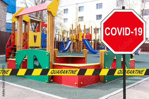 Concept ''COVID-19'' road sign and a quarantine warning tape against a closed playground