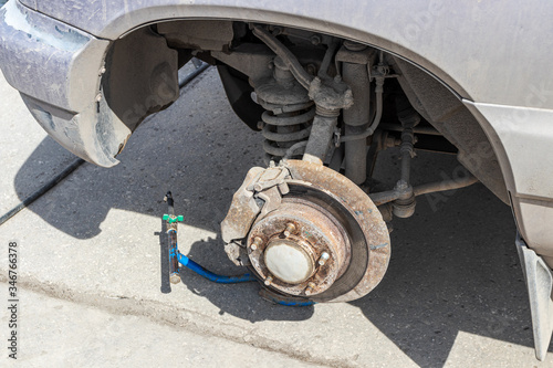 Front axle of the crossover raised by a pneumatic jack during wheel replacement