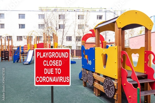 ''Playground closed due to COVID-19'' information sign against a closed playground