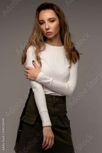 Beautiful portrait of young model with curly hair on grey background in white shirt