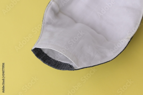 detail of cloth mask material with white salu muslin fabric soft textile, objects put on yellow background photo