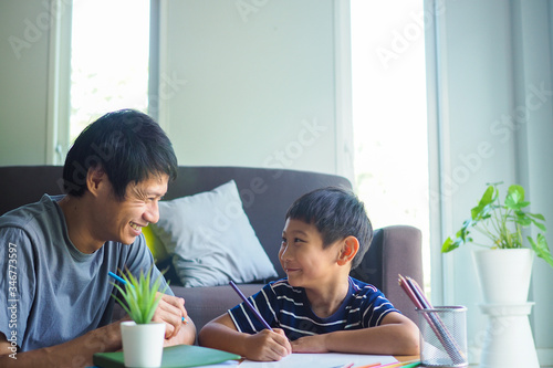 Family and homework concept. Happy father and son with book writing to study at home. photo