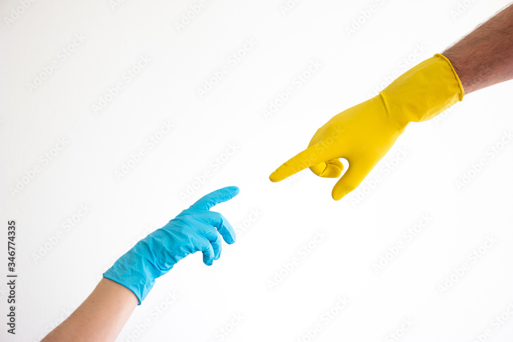 Caucasian woman and man hands and arms in blue and yellow latex gloves pointing index fingers at each other isolate on white Caucasian woman and man hands and arms in blue and yellow latex gloves pointing index fingers at each other isolate on white