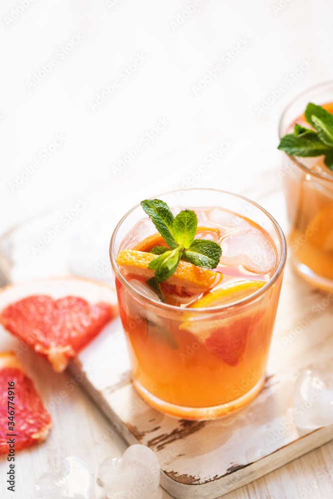 Grapefruit cocktails with mint and ice. Cold summer citrus fresh beverage on light wooden background Grapefruit cocktails with mint and ice. Cold summer citrus fresh beverage on light wooden background