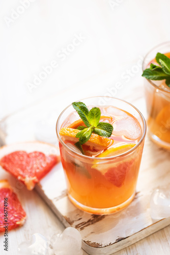 Grapefruit cocktails with mint and ice. Cold summer citrus fresh beverage on light wooden background