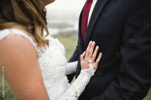 Romantic, fairytale, happy newlywed couple hugging and kissing in a park, trees in background