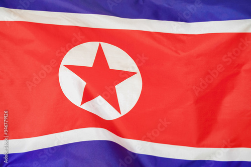Fabric texture flag of North Korea. Flag of North Korea waving in the wind. North Korea flag is depicted on a sports cloth fabric with many folds. Sport team banner.