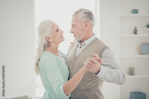 Profile side photo of charming spouses wear teal brown pullovers look in eyes move like in dance floor stand in their room apartment