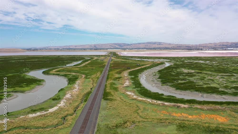 Railroad tracks straight down majestic green wetlands, aerial approach Railroad tracks straight down majestic green wetlands, aerial approach
