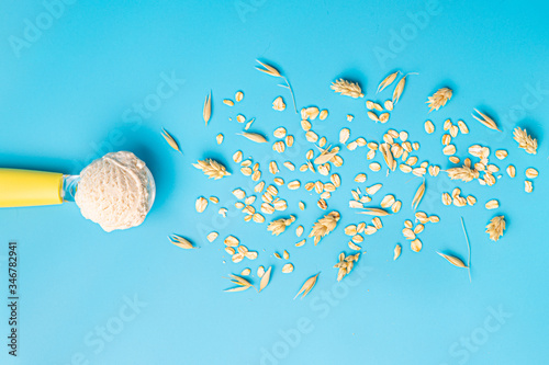 oat milk ice cream ball and oat seeds on blue background, horizontal