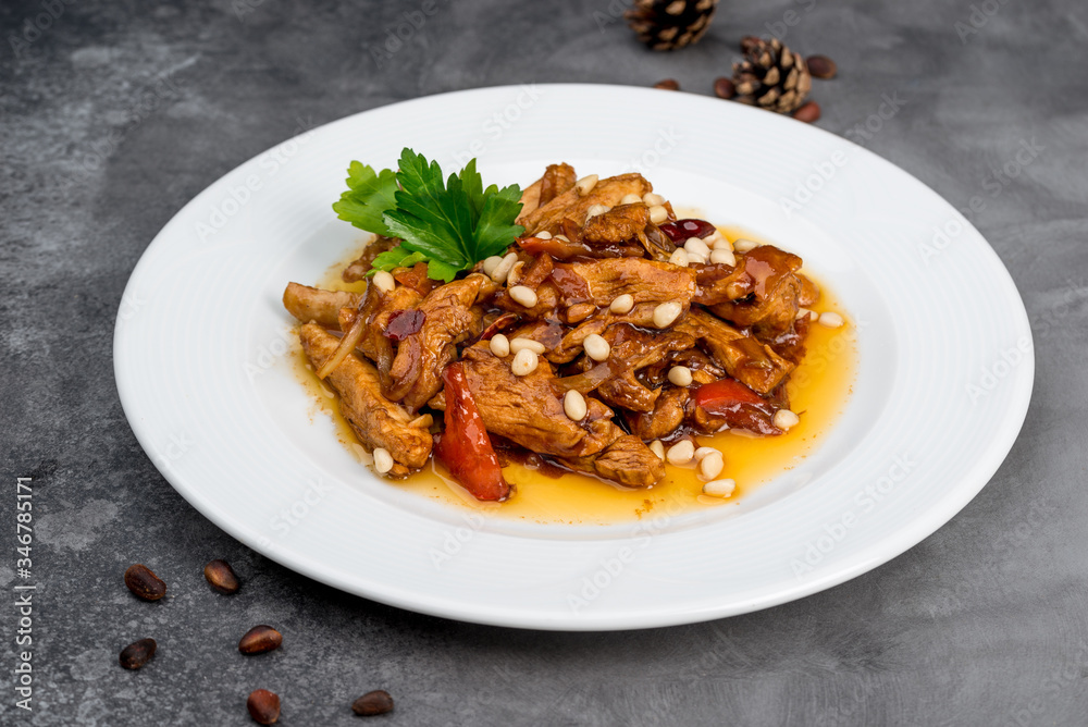 Cooked chicken fillet with pine nuts in a white plate