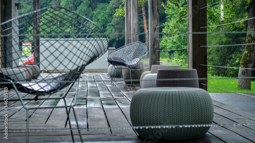 Outdoor terrace with cozy wicker and metal chairs for relaxation on a rainy spring day