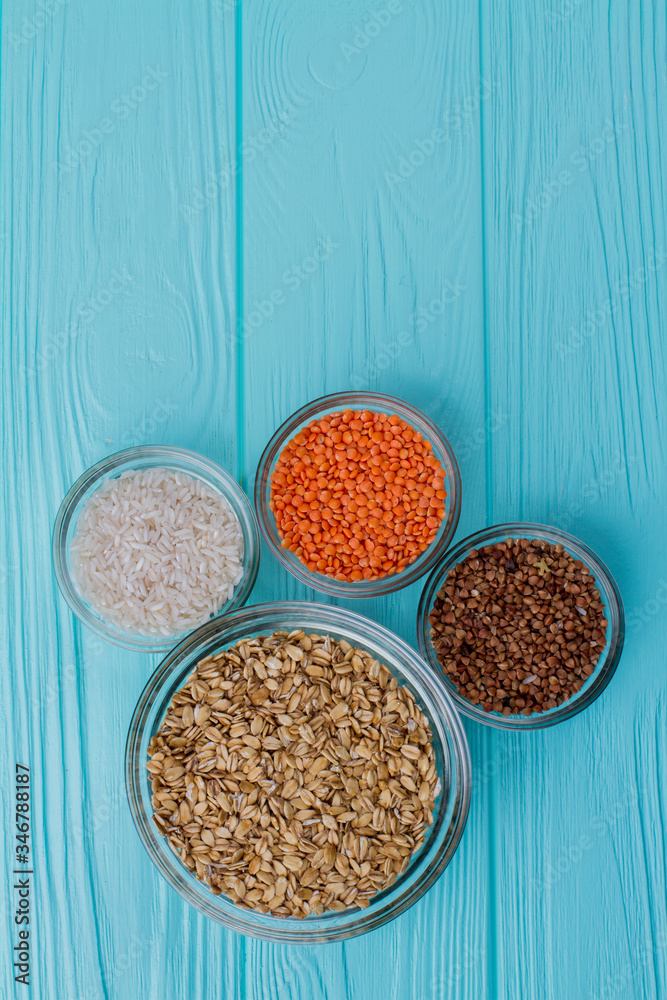 Glass plates with different grains top view. Blue wooden background with copy space. Glass plates with different grains top view. Blue wooden background with copy space.