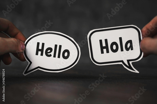 hands hold pieces of paper with the words hello and hola