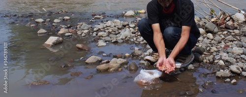 Panoramic view on the river bank. a man was squatting on the riverbank holding fish seeds.