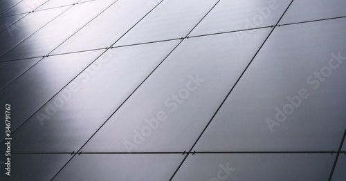 wall of modern building covered with grey panels at sunlight on city street
