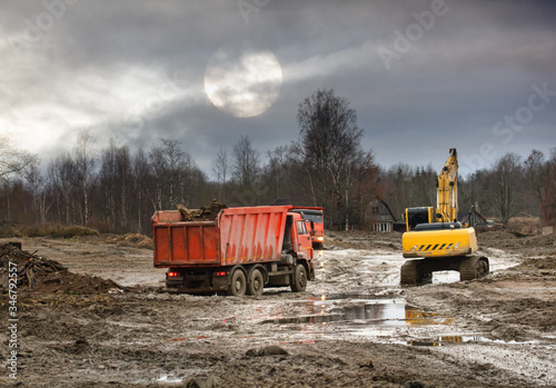 Excavator loads excess soil into dump trucks photo