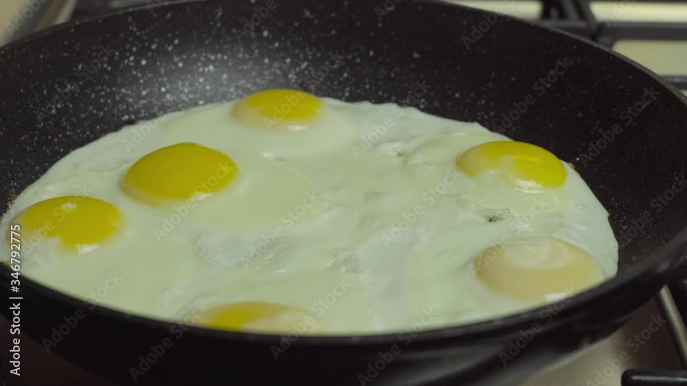 Fried eggs in a pan. A female hand lifts the lid of a pan with a condensate. Fried eggs in a pan. A female hand lifts the lid of a pan with a condensate.