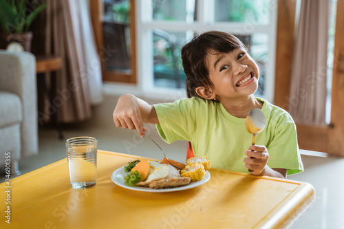 happy young kid smiling to camera while having healthy breakfast at home