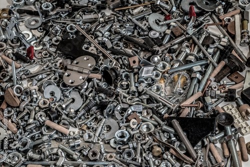 Various and numerous scraps, pins, screws, nuts, bolts and washers placed all together on a wooden plank