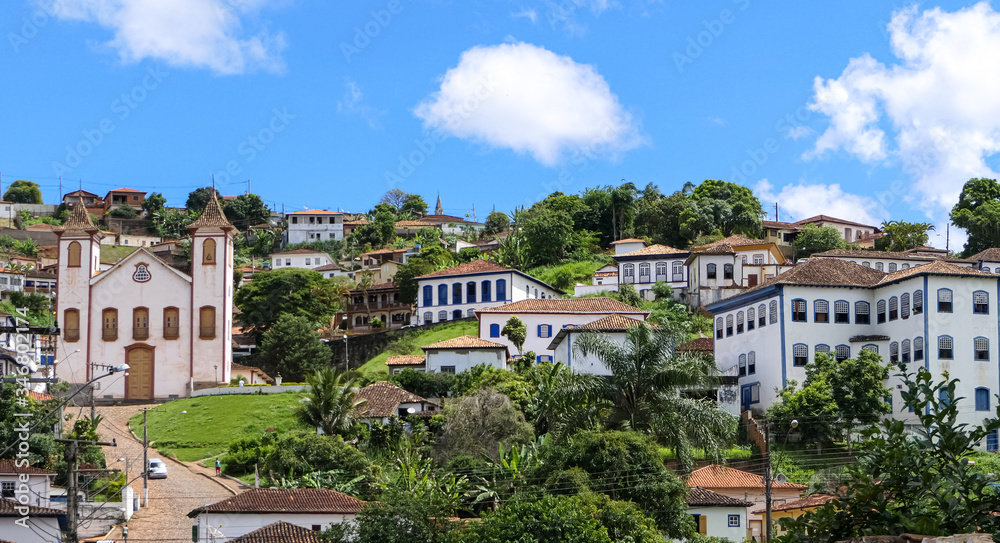 View to historic mining town Serro nestled on a hill, blue sky and white clouds, Minas Gerais, Brazil
